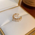 Dettaglio di un ear cuff dorato a doppio strato con texture a treccia e perle bianche - Oro