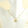 Dettaglio della collana con ciondolo occhio greco dorato, zirconi neri e perle su modella - Occhio di Perla (NE2000)