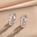 Orecchini a cerchio in argento con pietre di zircone su uno sfondo beige testurizzato - Orecchini a Serpente Argento (8953)