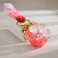 Detail of pink cat paw liquid keychain with glitter, golden bell and silicone strap - Quicksand Luminous Style / Rose Red