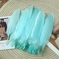 Light blue decorative goose feathers for DIY crafts on a natural straw mat backdrop - Stiff Light Blue (50Pcs)