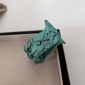 Matte mint green claw clip with black ink splatter pattern in a minimalist display box - Small Blue