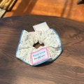 Close-up of blue polka dot fabric scrunchie with Keep Love label on wooden background - White Scrunchie with Blue Trim and Blue Polka Dots