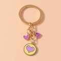 Detail of a golden keychain featuring three heart pendants with purple enamel finish - Yellow & Purple