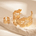 Detail van de gouden ginkgo blad manchetarmband en bijpassende ring op een stenen voet - Armband Ring Set (Goud) / Goud