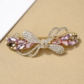 Elegant gold bow hair clip with purple crystals and pearls on a textured background - Bai Yue Colorful