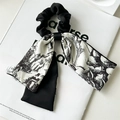 Détail d'un chouchou en satin noir avec ruban à motif floral rétro élégant - Imprimé Noir et Blanc