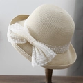 Dettaglio di un cappello di paglia beige intrecciato con un grande fiocco di pizzo a pois - 56-58cm / Beige