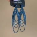 Détail macro des boucles d'oreilles pompons en strass bleus avec design en U à trois couches - Bleu