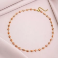 Detail of gold evil eye necklace with orange beads and lobster clasp on pink fabric - Orange