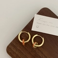 Detailed shot of gold hoop earrings with orange enamel ring charms on dark wood - Orange Single Hoop Earrings