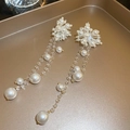 Detailed close-up of elegant long pearl tassel earrings with gold finish on a tray - White Flower Faux Pearl