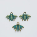 Detailed view of three vintage alloy bee pendants with bronze finish and teal enamel accents - Antique Green