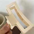 Detail van een grote crèmekleurige matte rechthoekige haarklem in de hand gehouden - Broken Wit