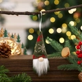 Close-up of green knitted gnome ornament hanging on a branch with warm festive lights - Green Style B
