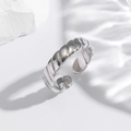 Close-up of a silver twisted copper ring with an adjustable open design on a stone - Thin Twisted Rope / Silver
