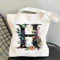 Detailed close-up of white canvas tote bag with floral letter H on a black chair - Letter H / 35*40cm