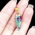 Natural ruby zoisite bullet stone pendant with gold clasp held by hand - Ruby Zoisite