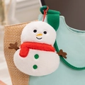 Close-up of a plush snowman charm with a red scarf hanging on a green bag strap - Snowman