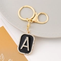 Detailed view of golden letter A keychain with black enamel and sparkling rhinestones - Letter A