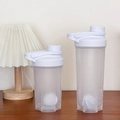 White protein shaker bottles with measuring scales and mixing balls on a wooden desk - White