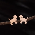 Rose gold stainless steel puppy dog ear studs displayed on a rustic wood branch - Sitting Puppy (786) / Rose Gold