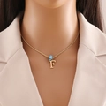 Model wearing a gold letter F pendant necklace with blue evil eye bead on a twisted chain - Letter F (N1339)
