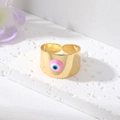 Vergulde open ring met boze oog en roze emaille op een witte getextureerde stenen voet - Roze Oog
