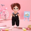 Princess doll in orange striped shirt and black overalls standing on pink background - Haining Girl