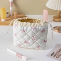 Detailed view of beige quilted cotton drawstring makeup bag with pink butterfly pattern - White Bow Pattern