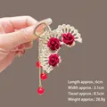Détail de la pince à cheveux dorée avec roses en velours rouge et glands de perles - M39 Rose en Forme d'Éventail