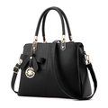 Black pebbled leather handbag featuring a bow ornament and golden circular pendant - Black