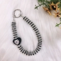 Black and silver beaded phone strap with heart pendant on soft white fabric background - Black Rhinestone Heart with Clear Center