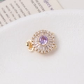 Macro detail of a 14K gold-plated flower clasp with purple gemstone and zircon inlay - Round / Double Row / Purple