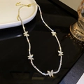 Collana a farfalla dorata con strass scintillanti su uno sfondo nero riflettente - Nappina a Farfalla in Strass Oro