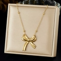 Dettaglio macro della collana con ciondolo a fiocco dorato su espositore premium - Stile Fiocco Lucido 3D (N3943)