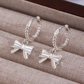 Macro view of silver bow-shaped drop earrings with beaded texture on jewelry organizer - Artificial Pearl Bowknot Style (G-258) / Bright Silver