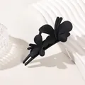 Detail of matte black butterfly duckbill hair clip on a white textured display stand - Double Butterfly Clip - Matte Black