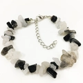 Macro shot of irregular black and clear tourmalinated quartz beads on an adjustable bracelet - Black Rutilated Quartz