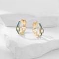 Detail of gold-plated hoop earrings with turquoise stones on a white stone background - Turquoise