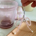 Close-up of pink crystal bow phone strap with silver star charm and white pearls - Pink Crystal Bow / Pink