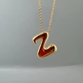 Polished gold metal initial Z pendant necklace close-up on a smooth gray background - Letter Z Single Pendant