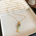 Détail du pendentif poisson doré avec émail bleu-vert sur une chaîne à billes élégante - Or-Bleu