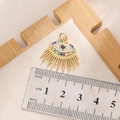 Golden evil eye pendant with blue zircon stones and tassels shown with metric ruler measurement - E002G