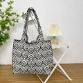 Detail of a large knitted tote bag with black and white geometric pattern on a white chair - Black Grid