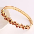 Detailed macro of 18K gold plated geometric cuff with marquise-cut red zircon stones - Red