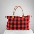 Detail of red and black plaid weekender bag with brown faux leather handles and gold hardware - Red/Black Plaid