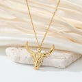 Close-up of golden bull head pendant necklace on white silk and natural stone background - Bull Head