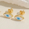 Macro shot of evil eye stud earrings with blue zircon on a textured stone surface - Blue Evil Eye