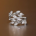 Detailweergave van zilveren ring met bladmotief en sprankelende zirkonia-kristallen - US 6 / Witgoud